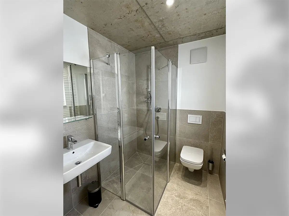 Modern eingerichtetes Bad mit Fußbodenheizung, Handtuchtrockner und bodengleicher Dusche.