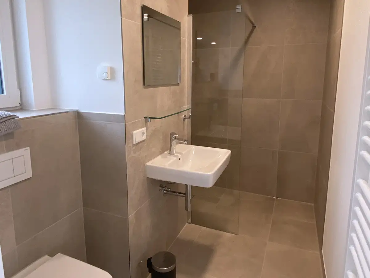 Bathroom with floor-level shower, underfloor heating and towel dryer